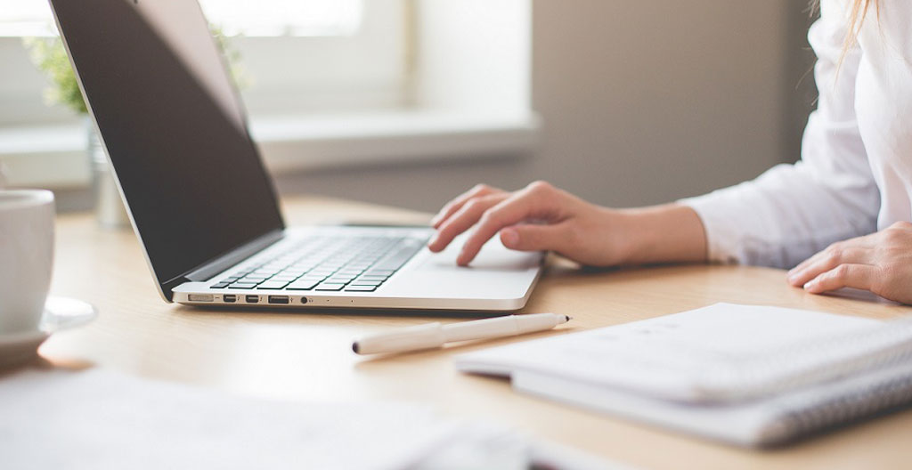 Gros plan sur un clavier d'ordinateur moderne avec un écran flou affichant du code en arrière-plan