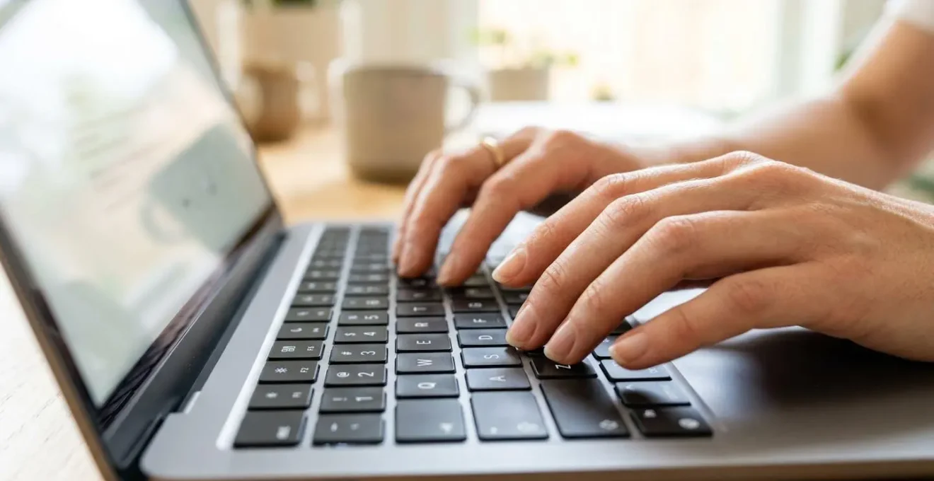 Gros plan sur des mains professionnelles tapant sur un clavier d'ordinateur portable moderne dans un environnement de bureau épuré